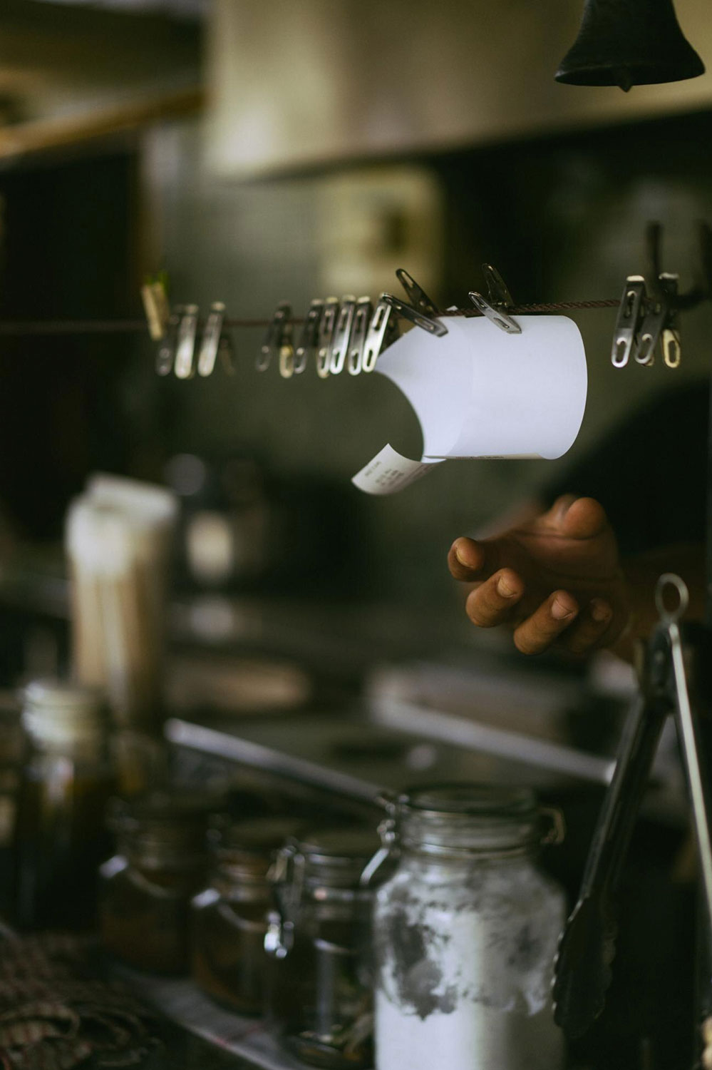 YellGO add-on stampa comande - comanda cartacea di un ristorante appesa in cucina con mano intenta a raggiungerla